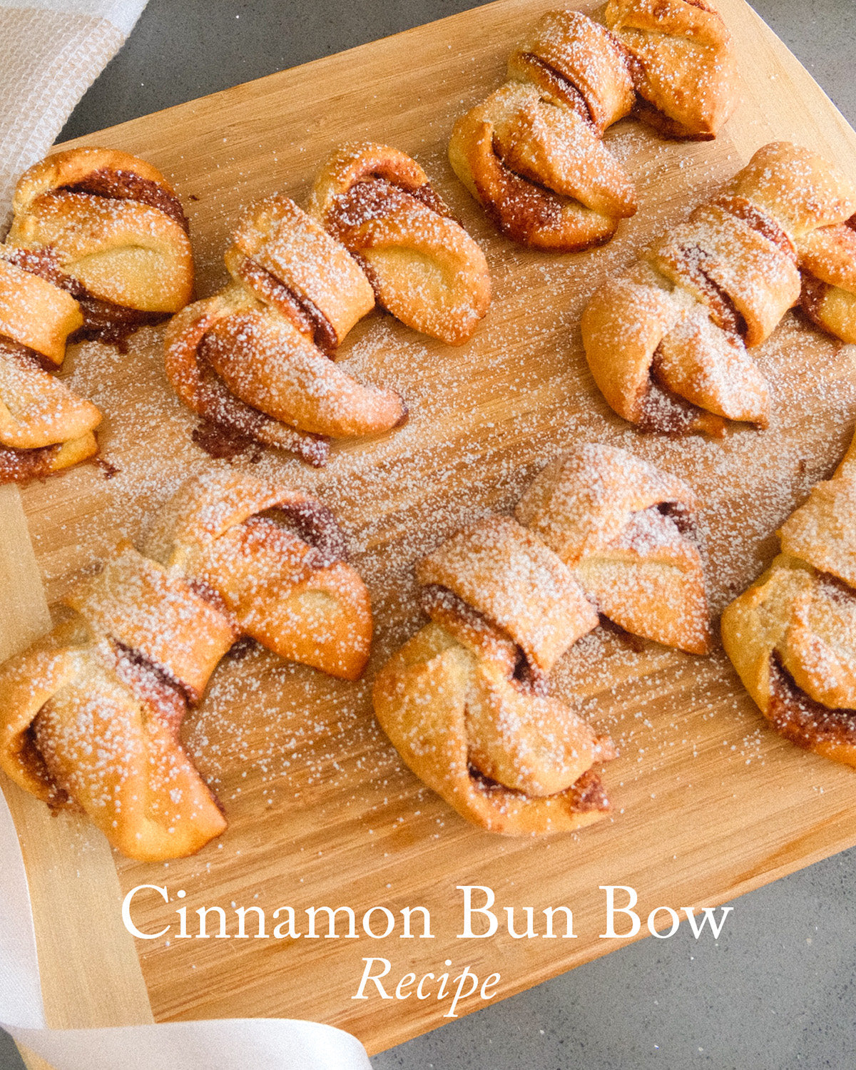 Vegan Cinnamon Bun Bow Recipe displayed on a wooden board with powdered sugar topping.