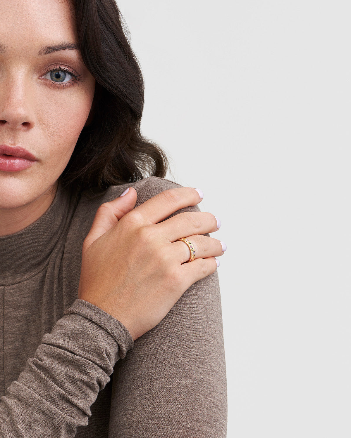 Woman wearing a gold ring on her finger with a neutral background