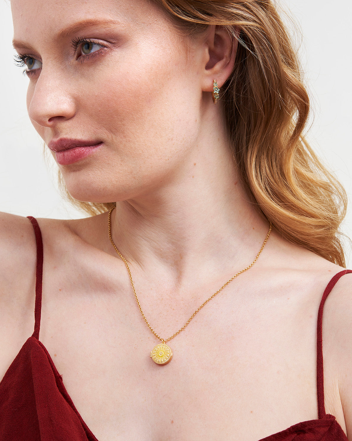 Model wearing a Gold Sun Locket Necklace showcasing a sunburst design and intricate detailing.