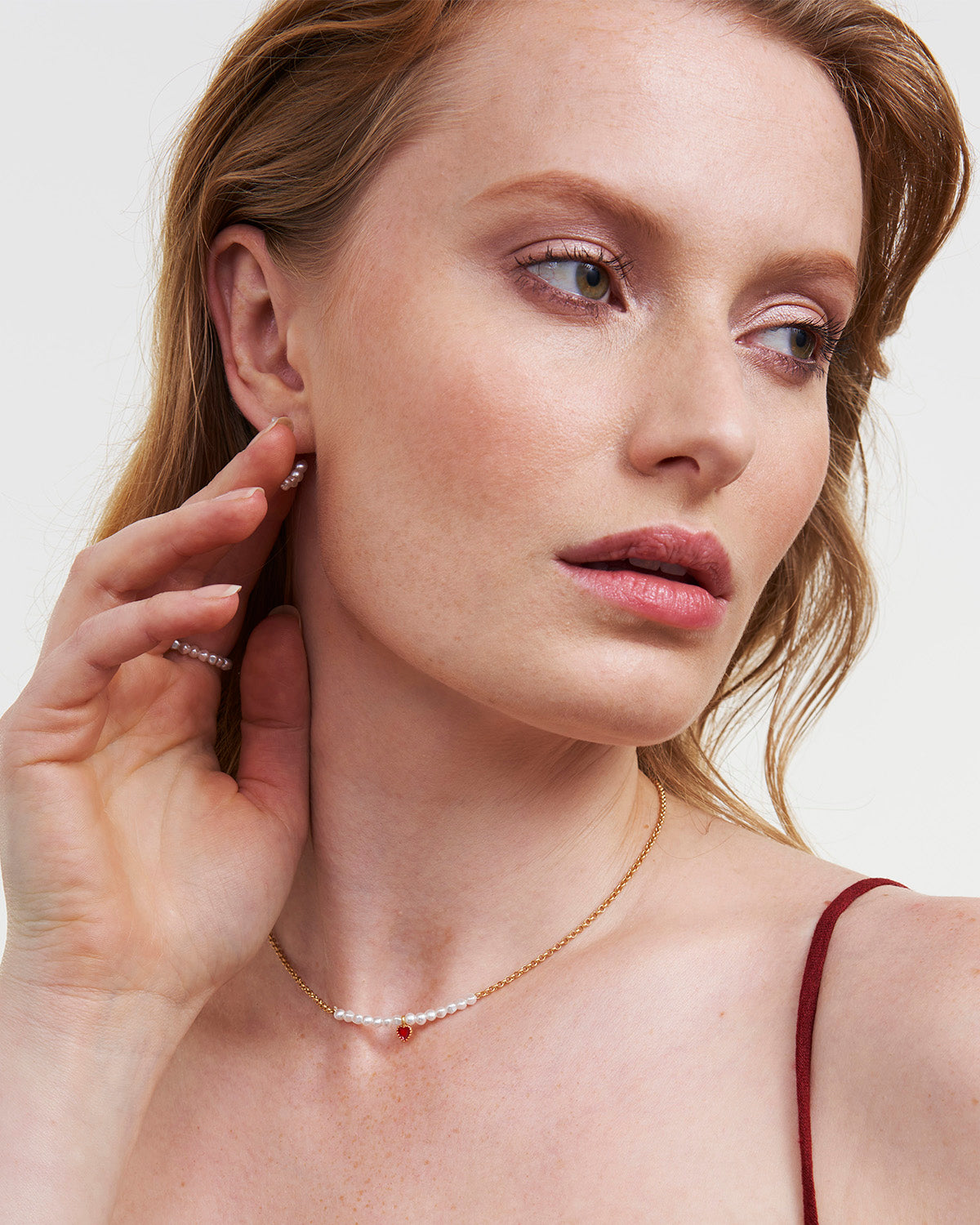 Gold Love Heart Pearl Necklace worn by a model, featuring pearl detail and red enamel heart pendant.