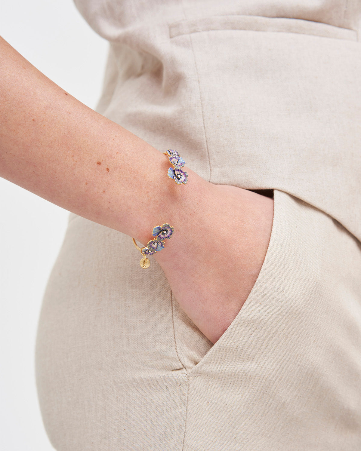 Gold bangle with purple pansy design on wrist