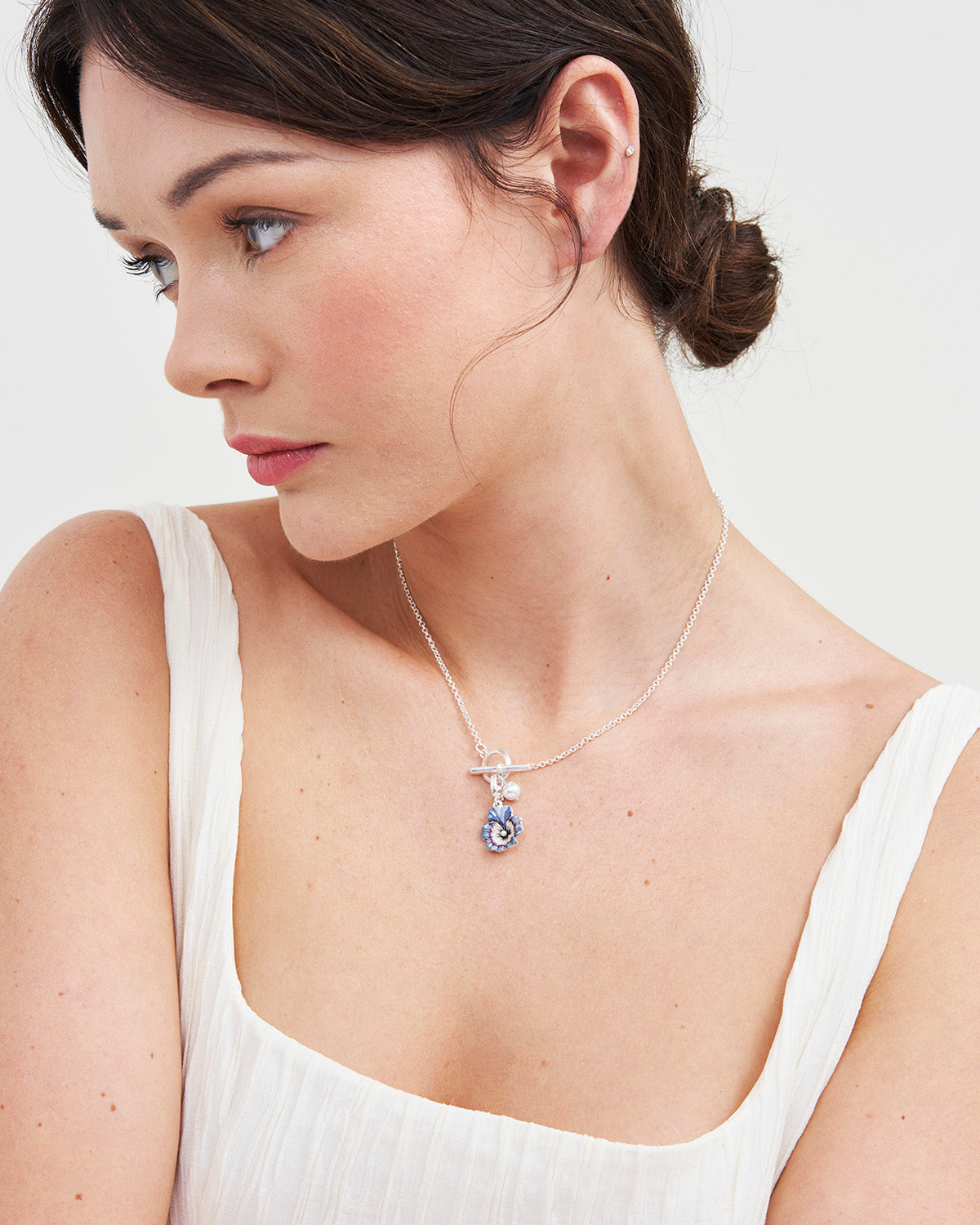 Model wearing silver pansy toggle chain necklace with white top on white background