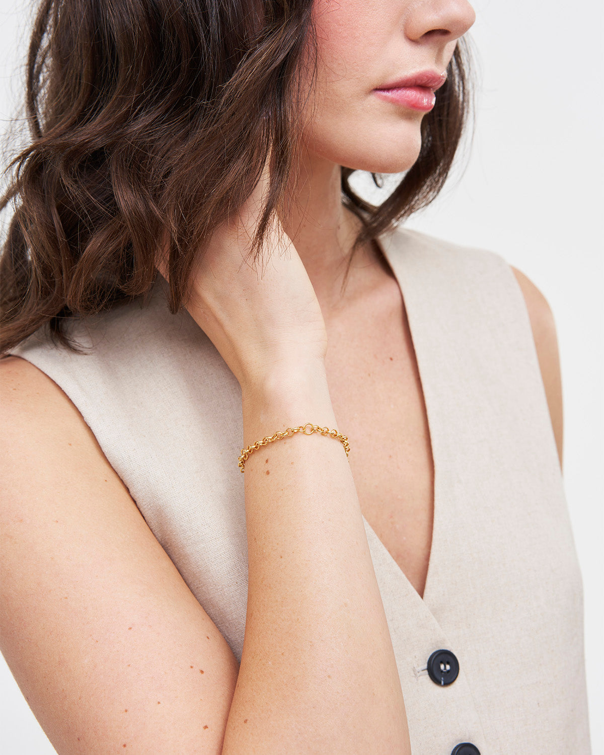 Woman wearing a Gold Charm Chain Bracelet on a plain background