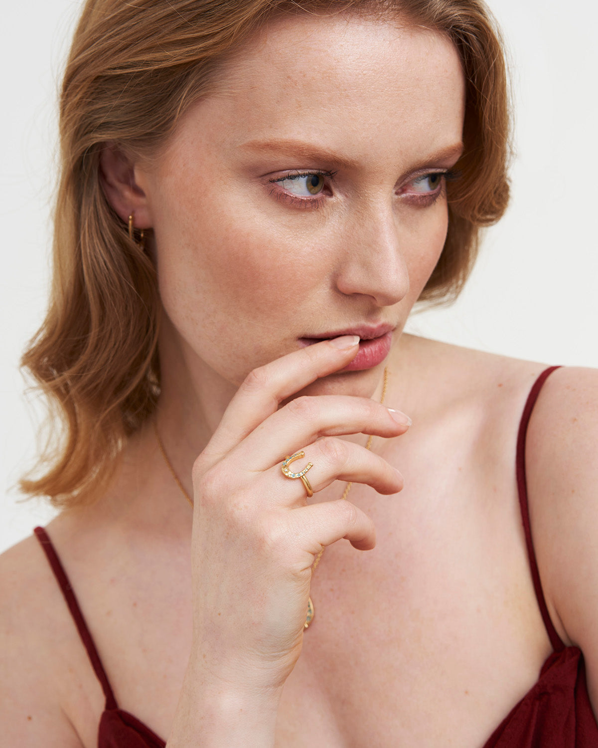 Woman wearing a Lucky in Love Gold Ring, showcasing its delicate horseshoe design with pearl and blue floral enamel.