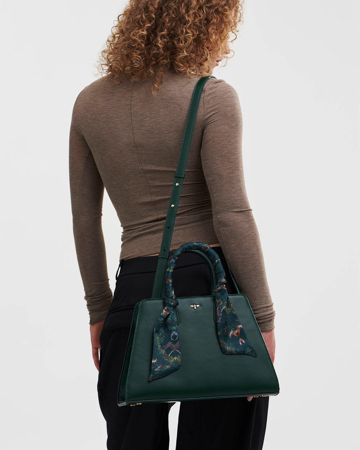 Woman holding a green handbag with floral details on a white background
