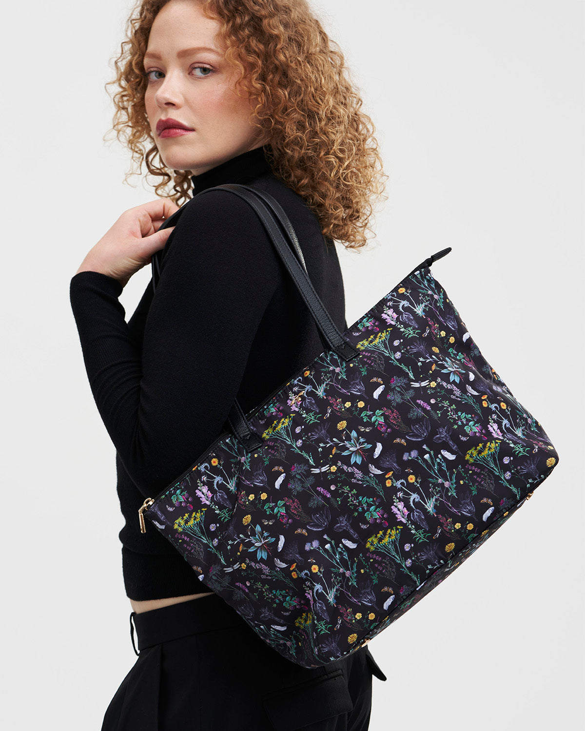 Woman carrying a floral-patterned bag on a plain background