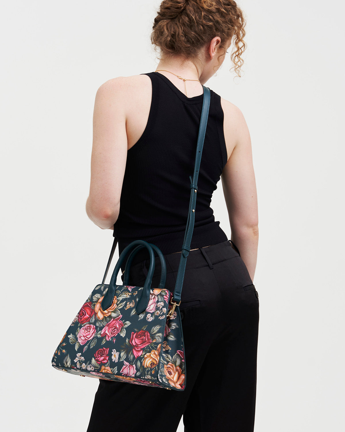 Person holding a floral-patterned handbag against a plain background