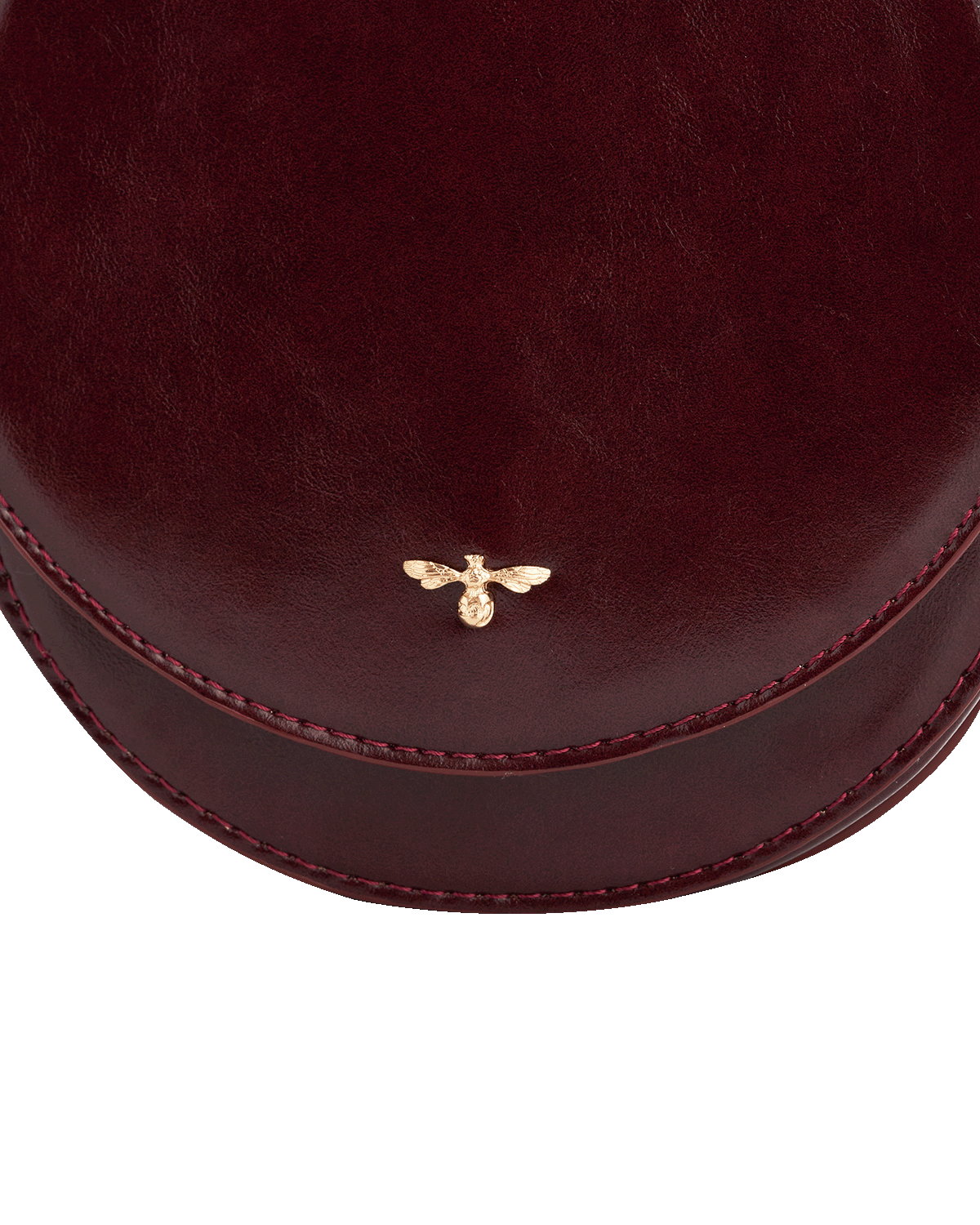 Round burgundy alternative to leather saddle bag with a gold bee emblem on a white background