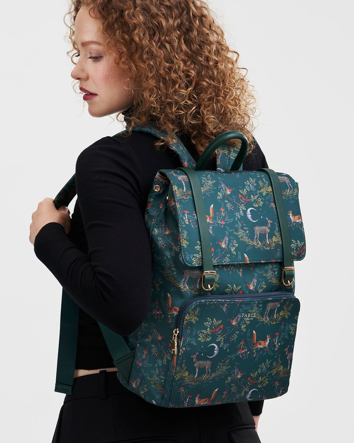 Person wearing a green backpack with nature-themed design on a white background