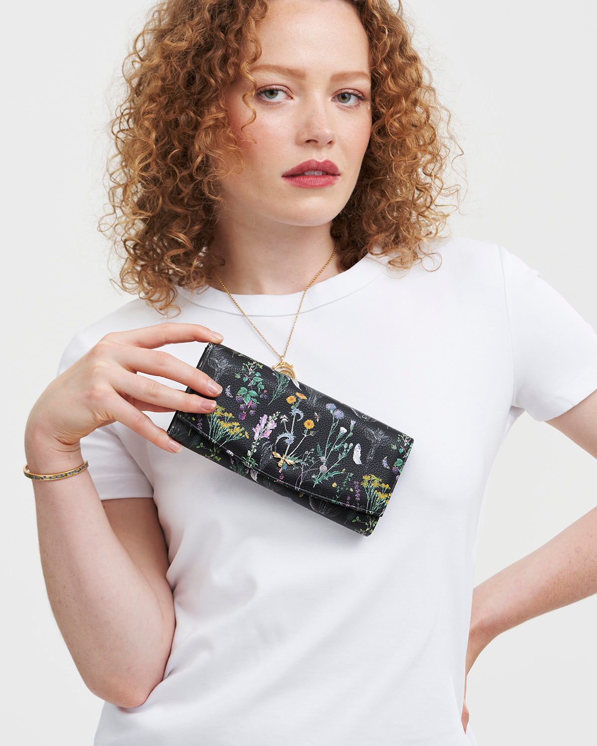 Woman holding a floral-patterned wallet against a white background