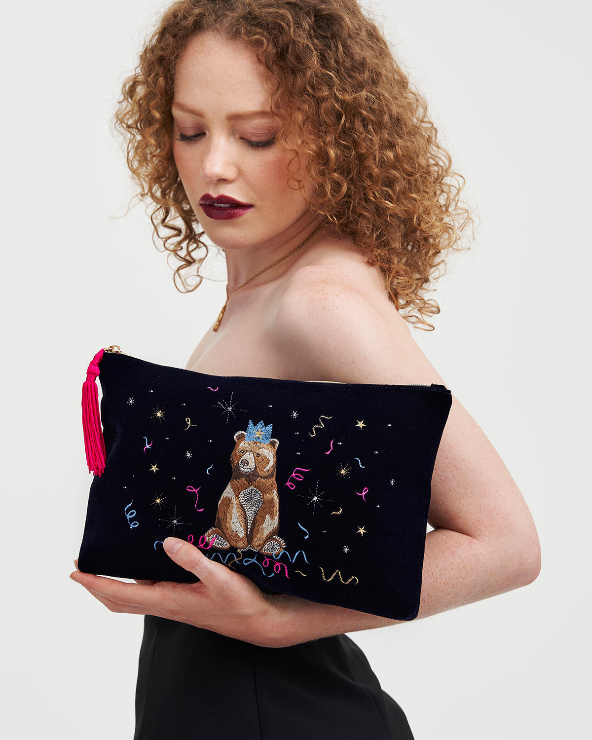 Woman holding a blue pouch with embroidered design on a white background