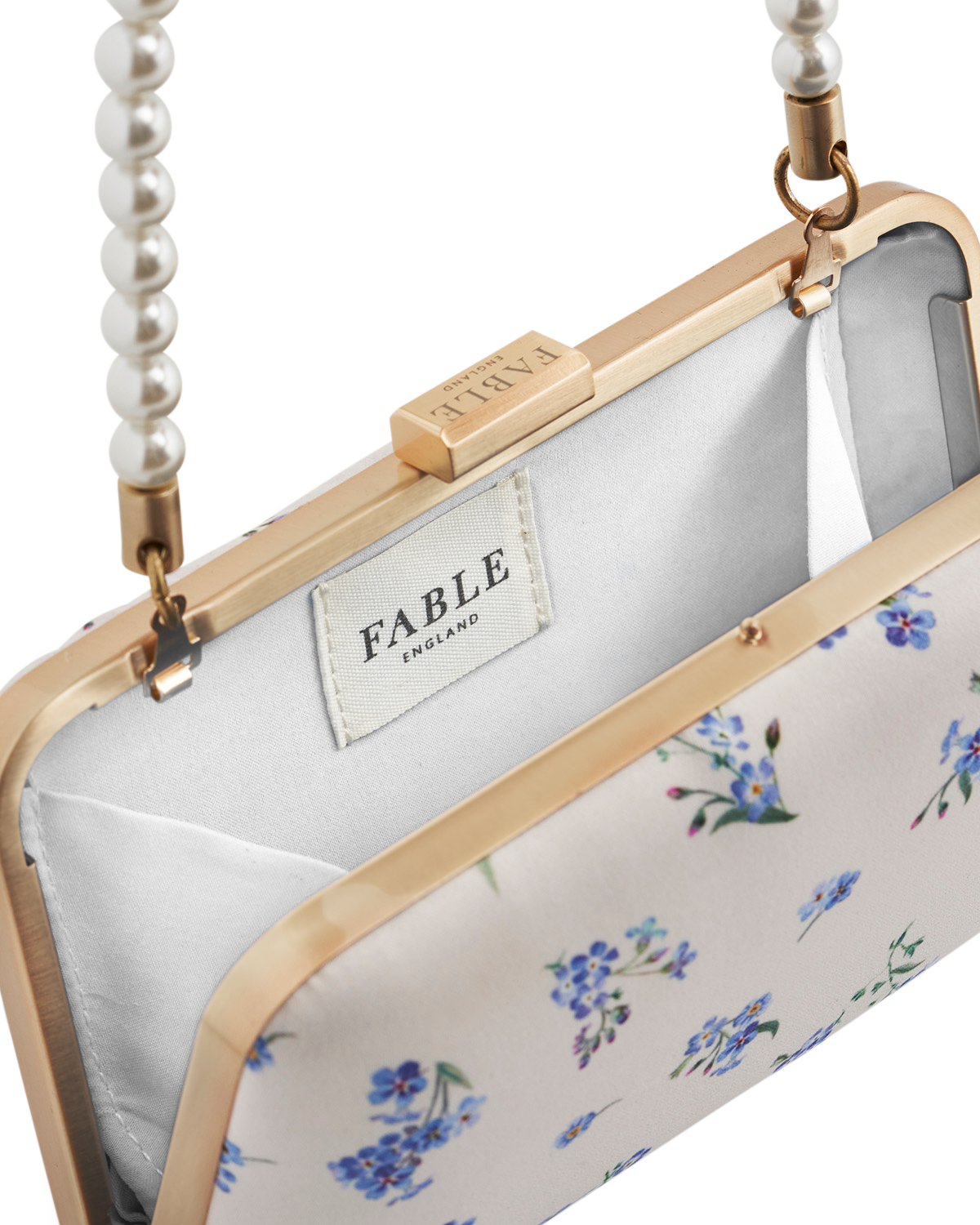 Floral clutch bag with pearl strap and 'Fable' label on a white background