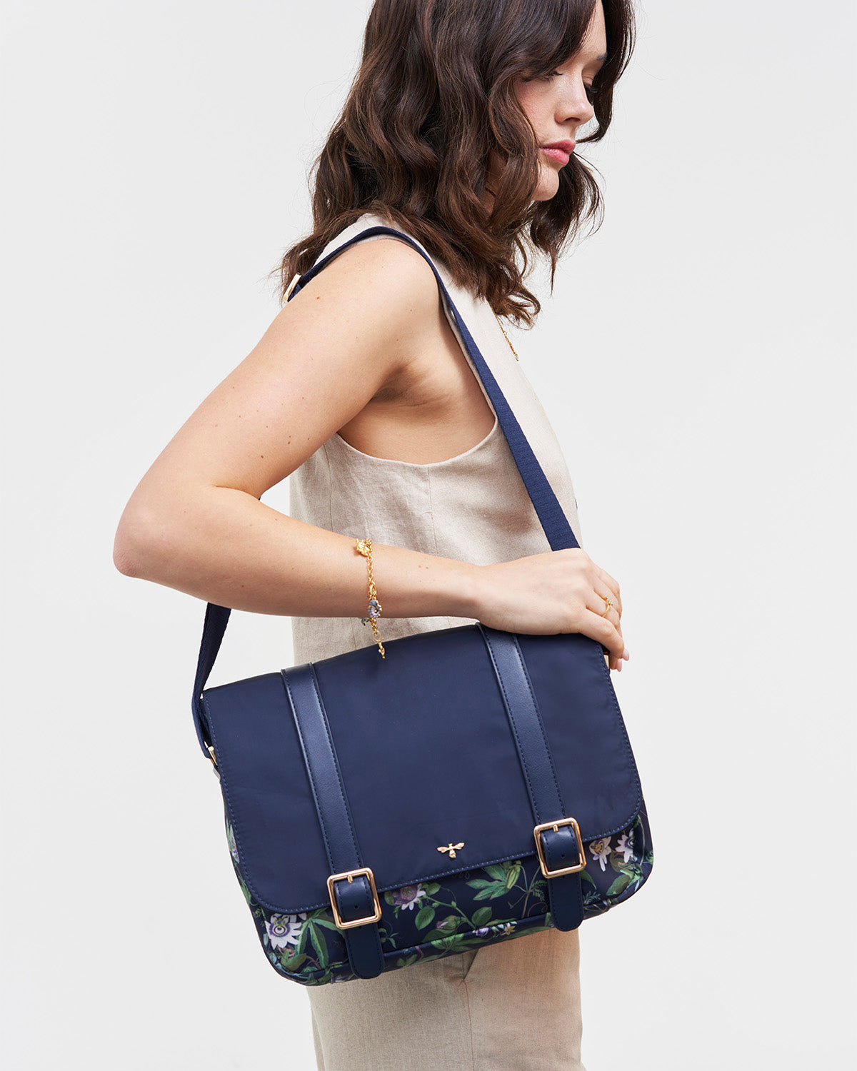 Woman holding a navy blue handbag with floral pattern on a white background