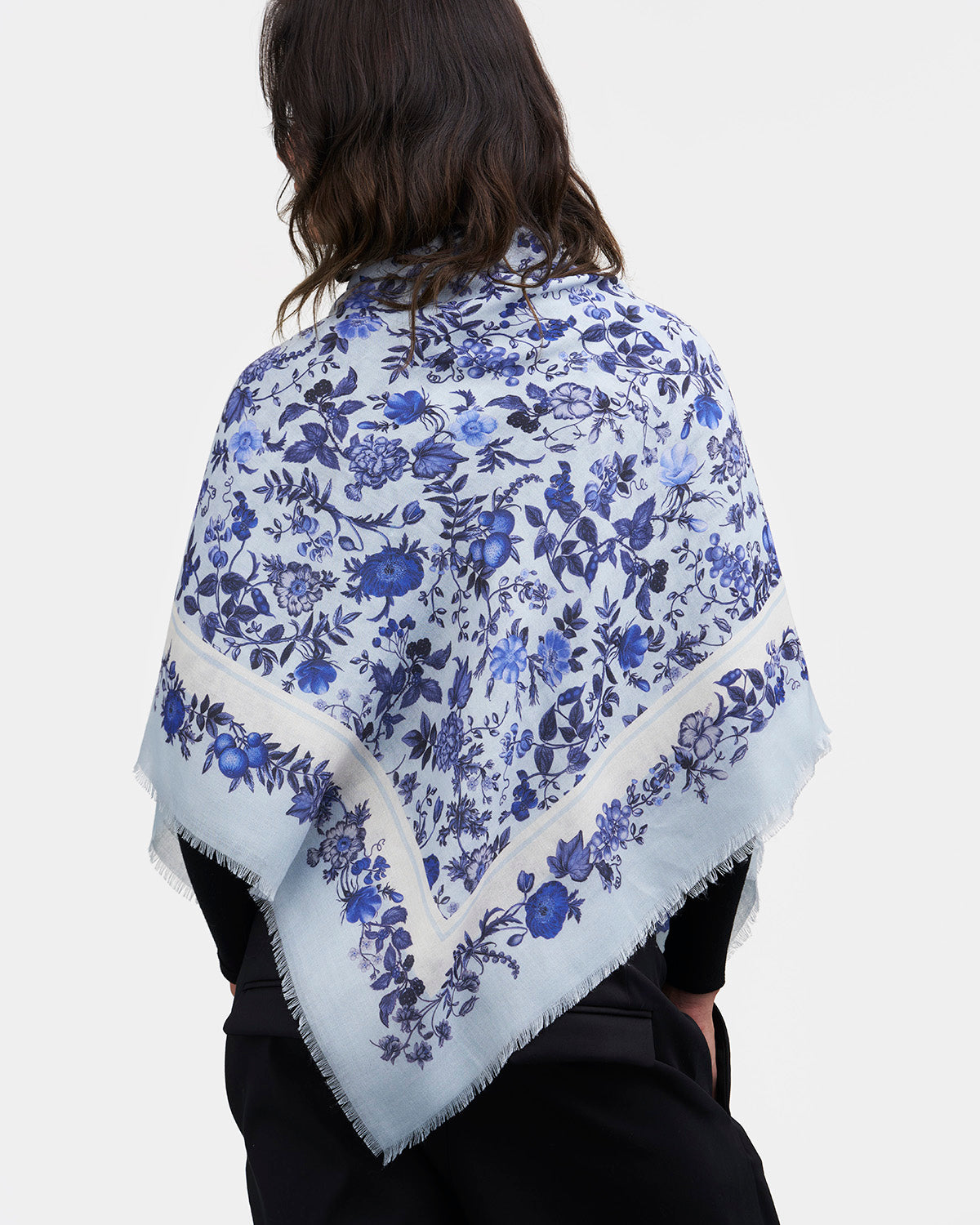 Person wearing a blue floral patterned scarf on a white background