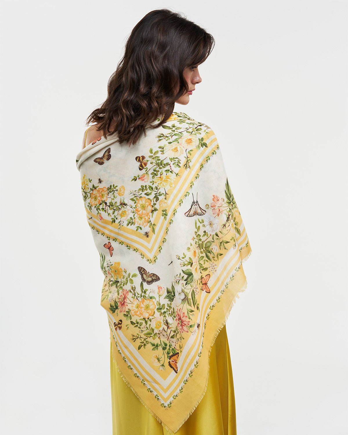 Woman showcasing a Yellow Cybele Narrative Square Scarf adorned with vibrant flowers and butterflies.