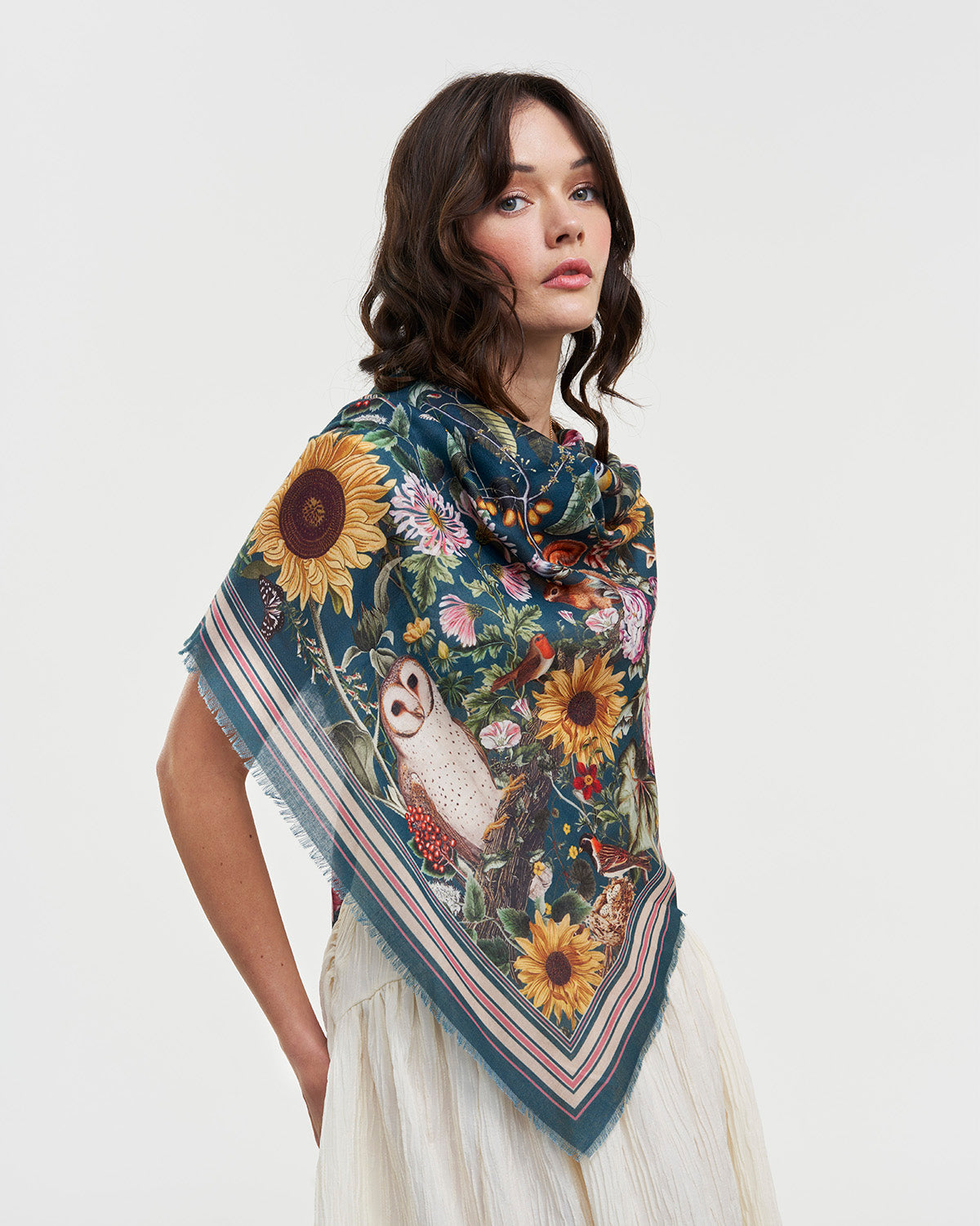Woman wearing a floral and nature-themed scarf on a white background