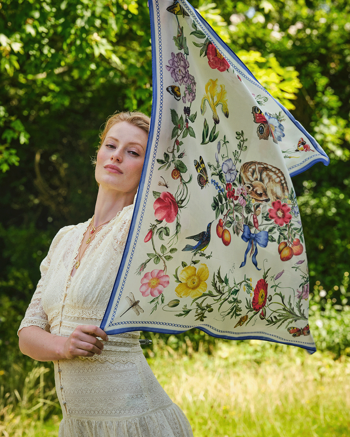 Woman holding a floral and nature-themed scarf outdoors