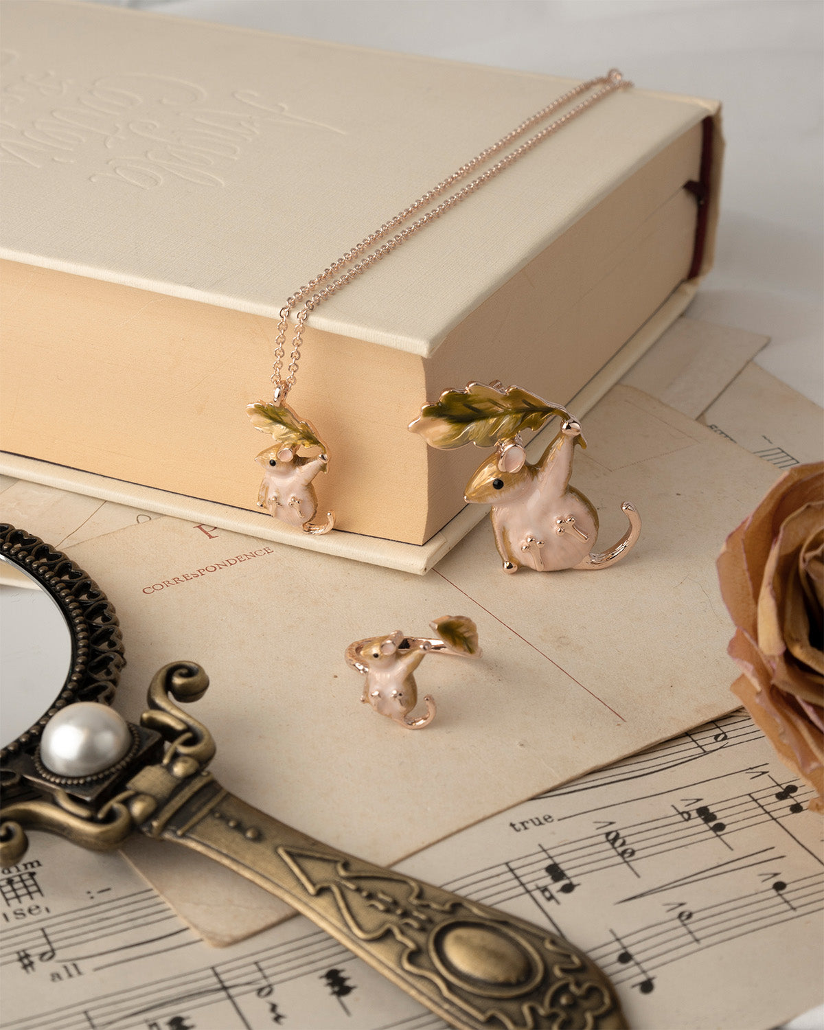 Small Dormouse enamel jewellery set on a book with sheet music underneath