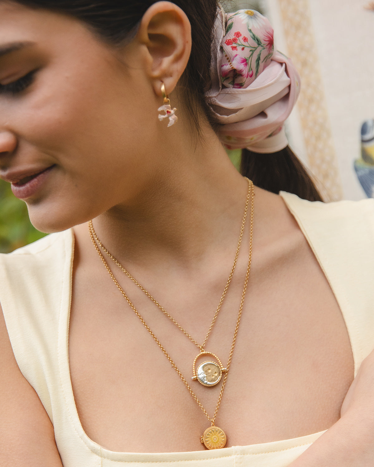 Woman wearing a gold necklace and earrings with a blurred background