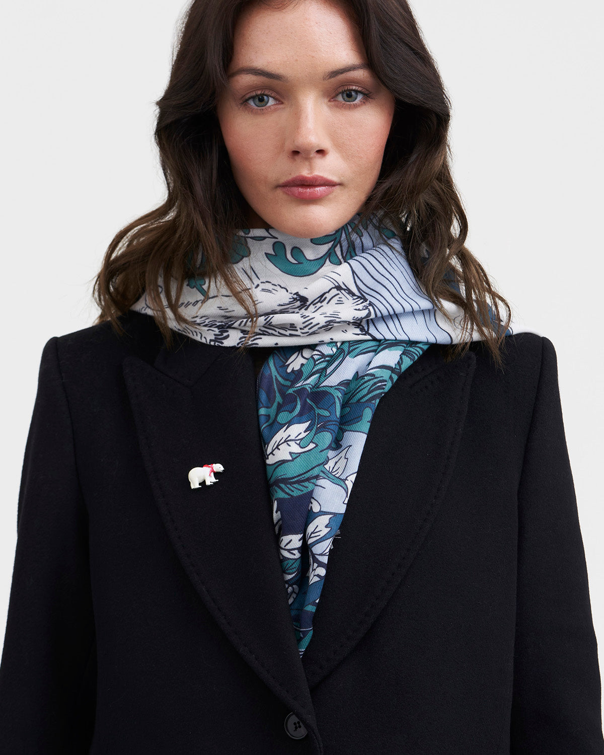 Woman wearing a patterned scarf and black coat on a white background