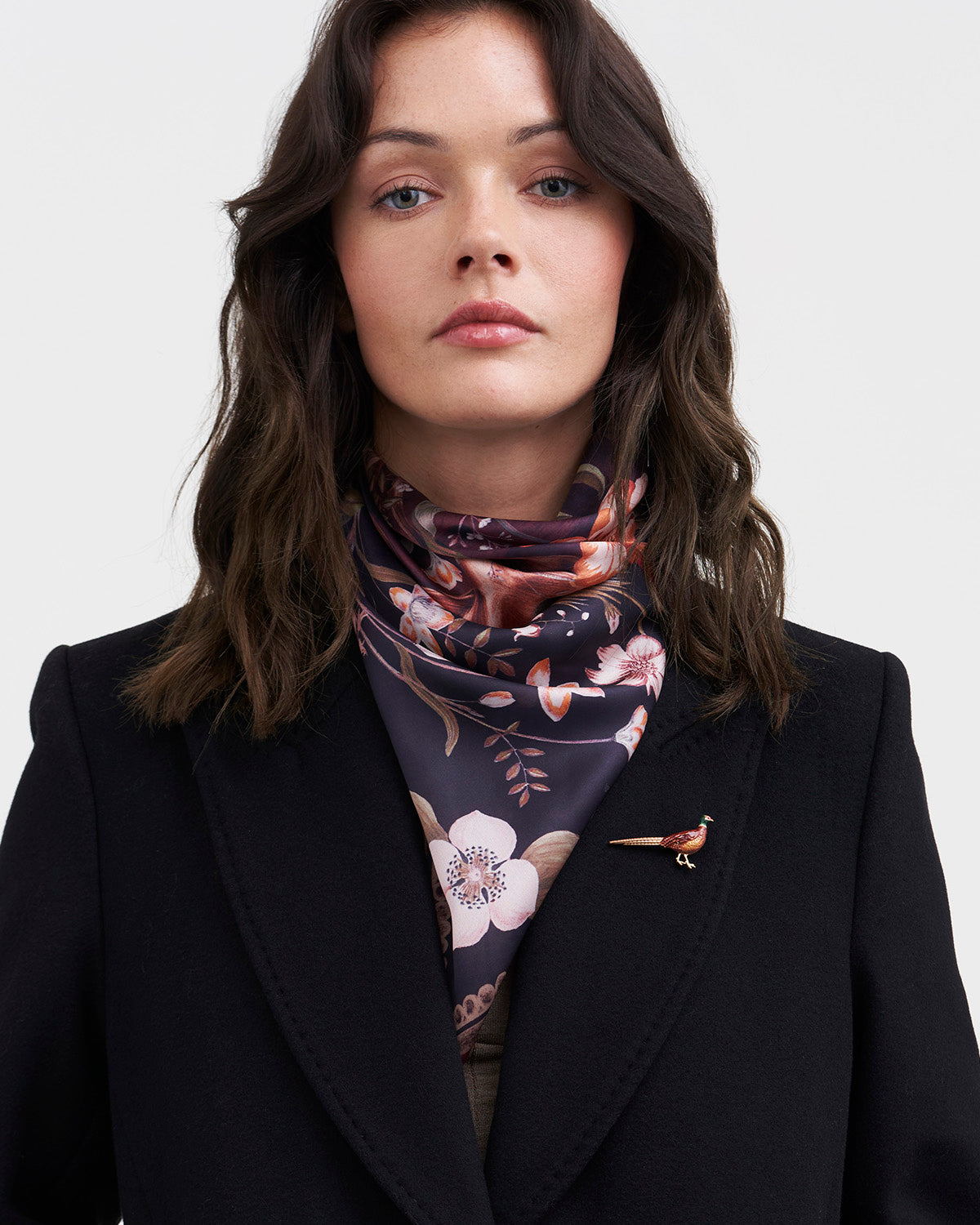 Woman wearing a dark floral scarf with a plain background