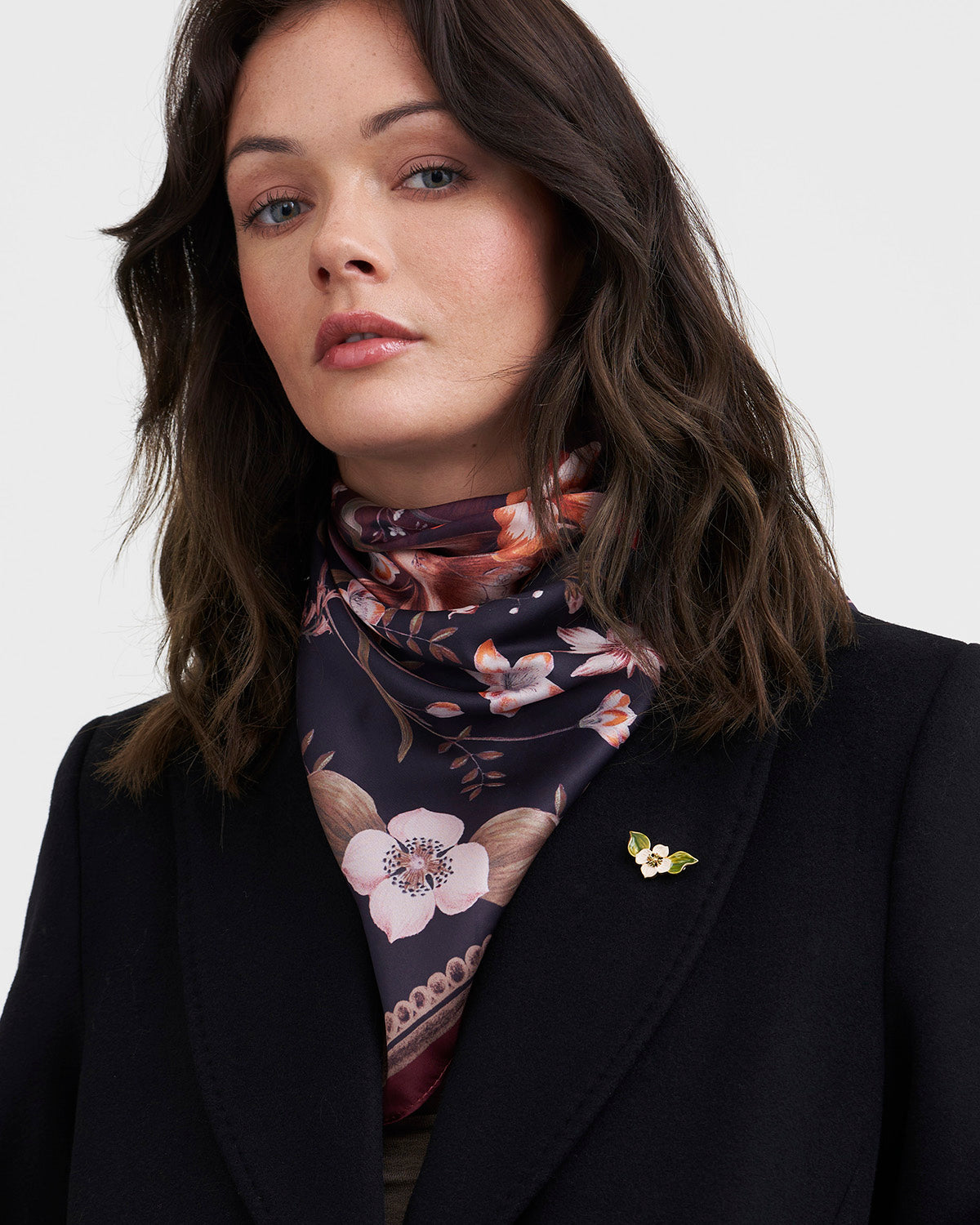 Woman wearing a floral scarf and black coat on a white background