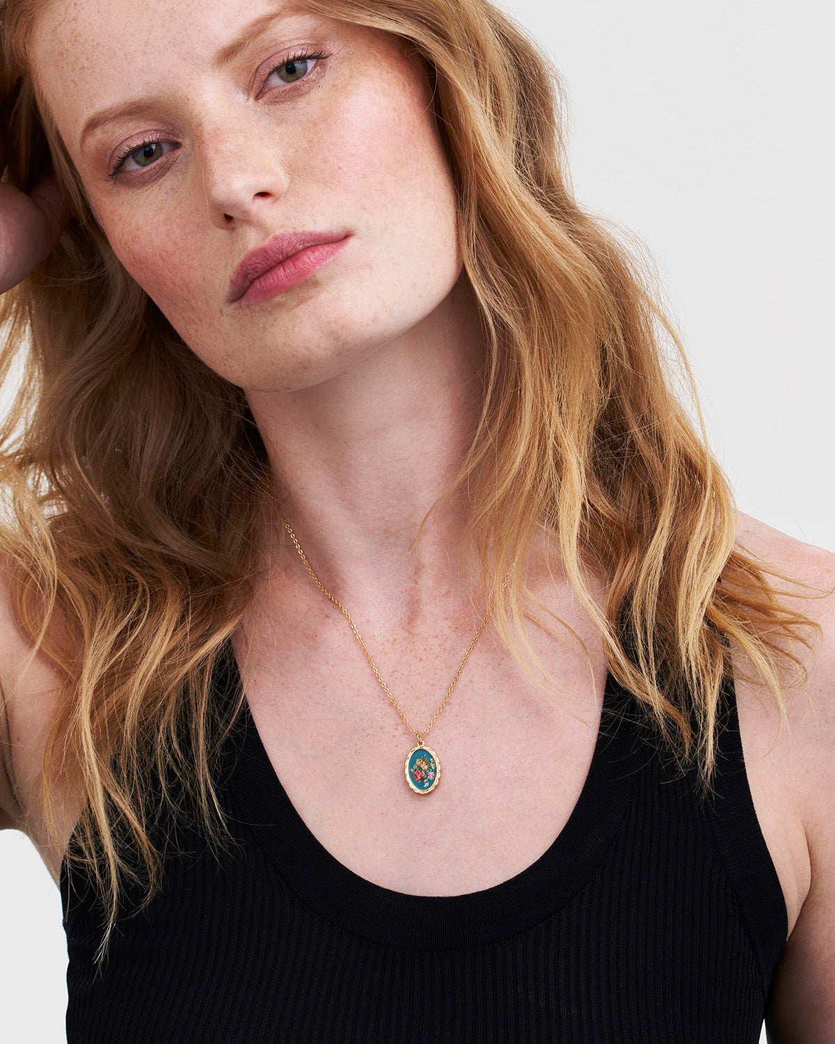 Woman wearing a necklace with a pendant against a white background