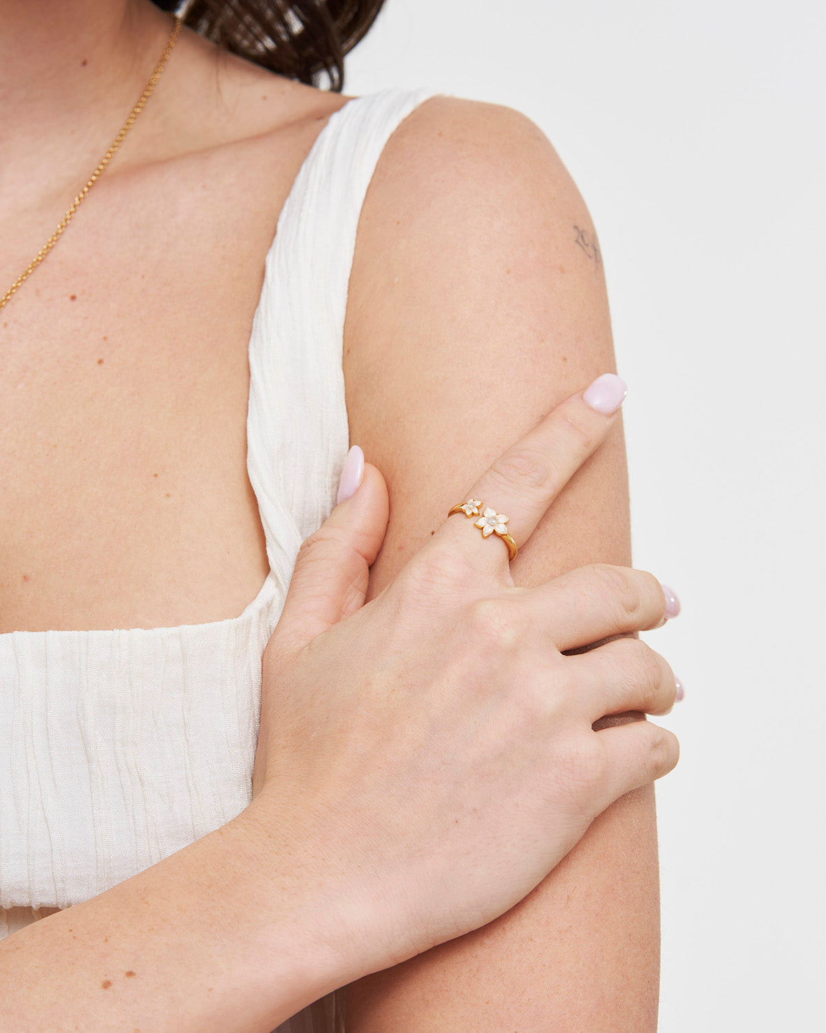Person wearing a gold jasmine ring on a white background