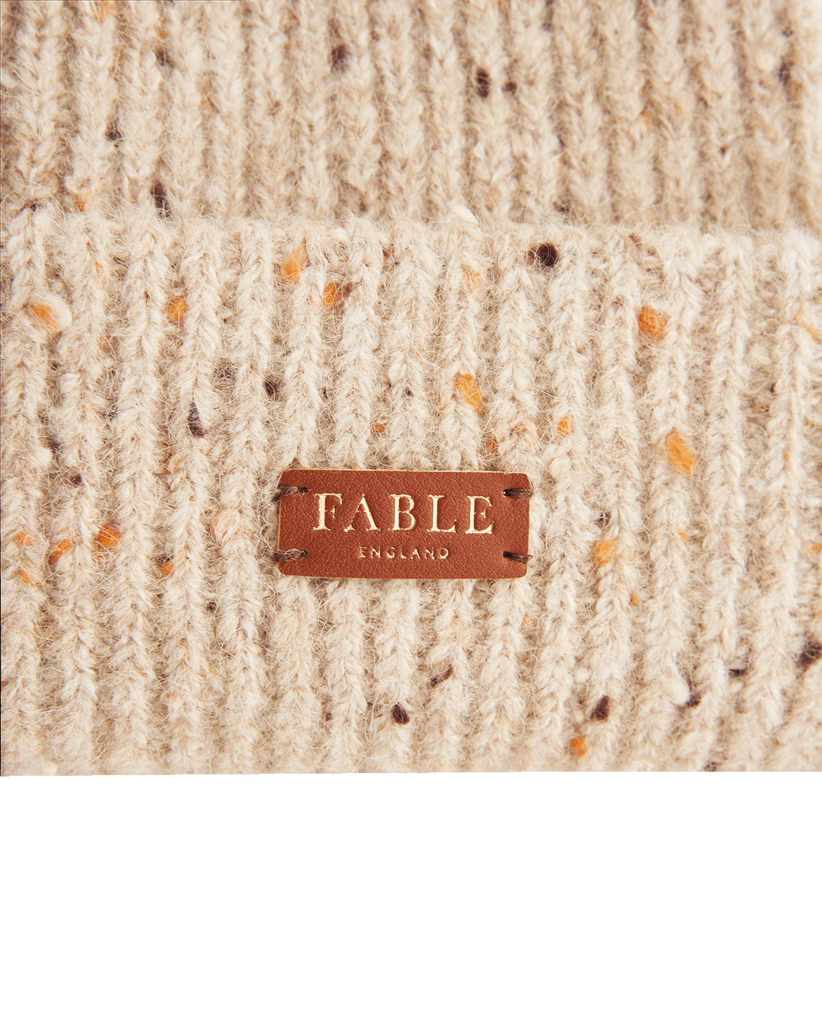Close-up of a textured hat with a 'Fable England' label on a white background