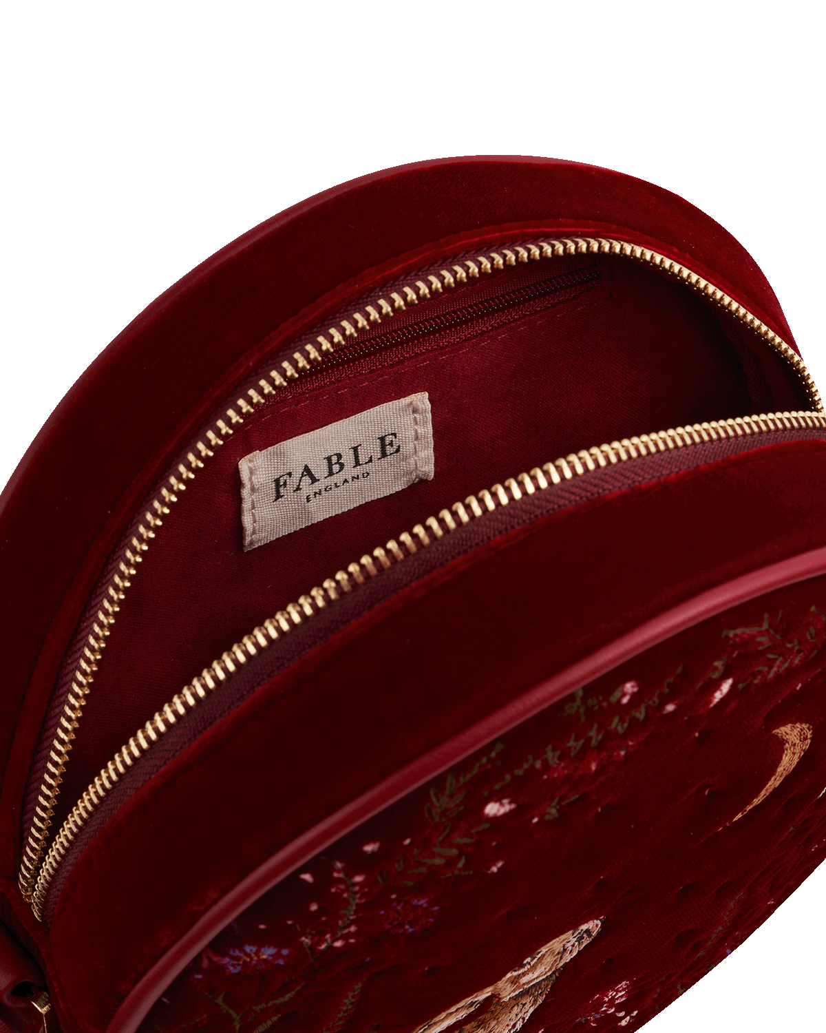 Close-up of a red handbag with gold zipper and 'Fable England' branding.