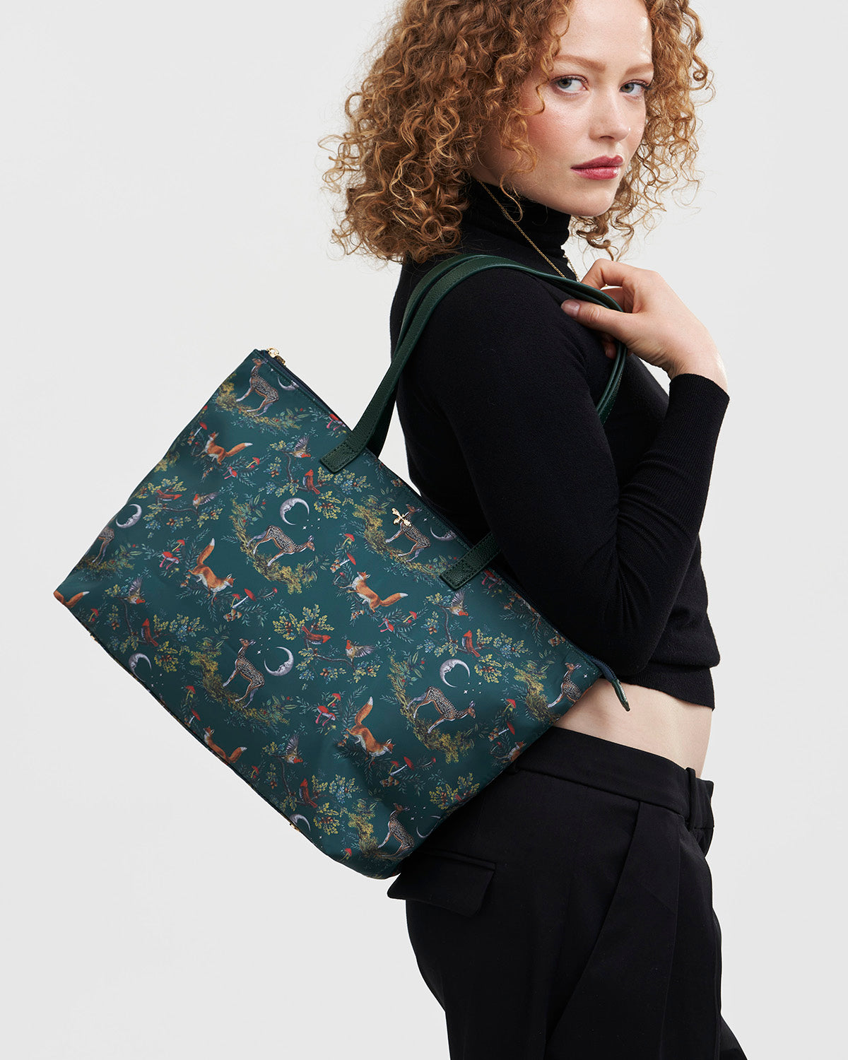 Woman carrying a woodland patterned tote bag on a plain background