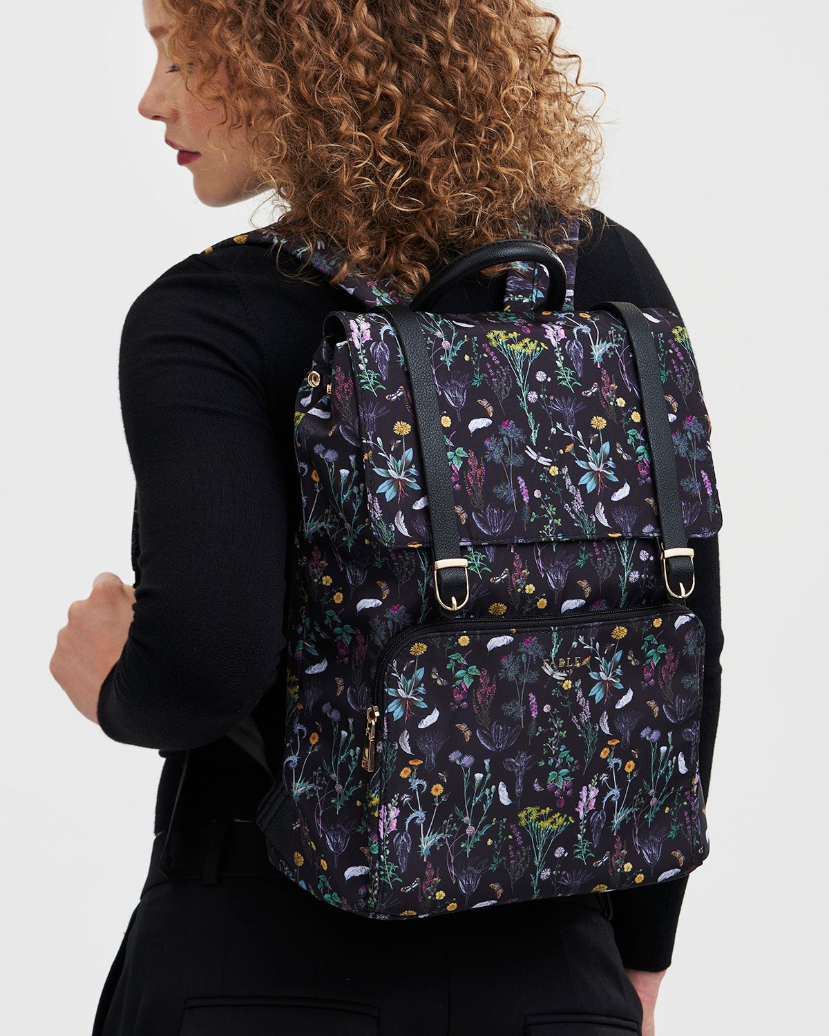 Person wearing a floral-patterned backpack on a plain background