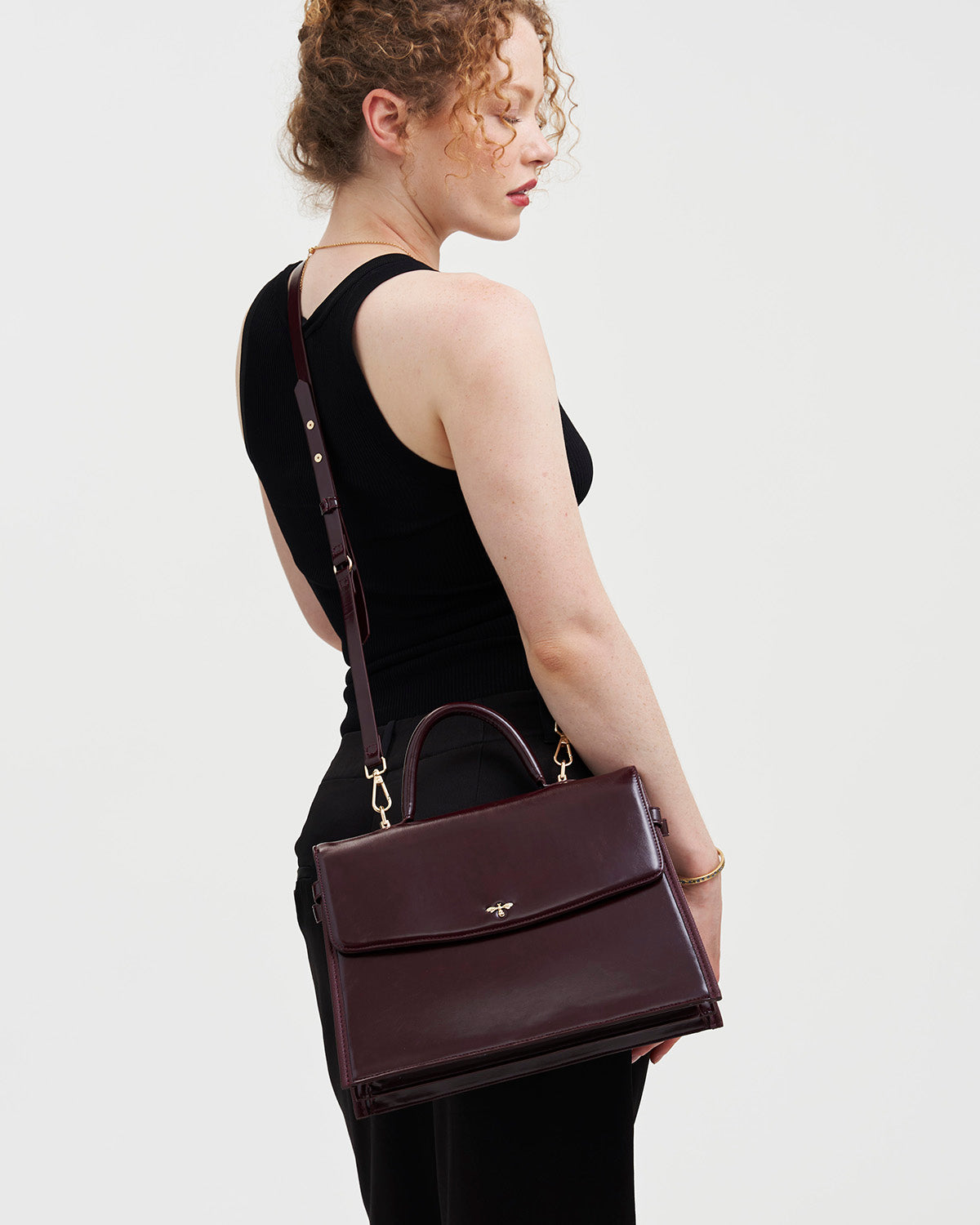 Woman holding a cherry red handbag against a plain background