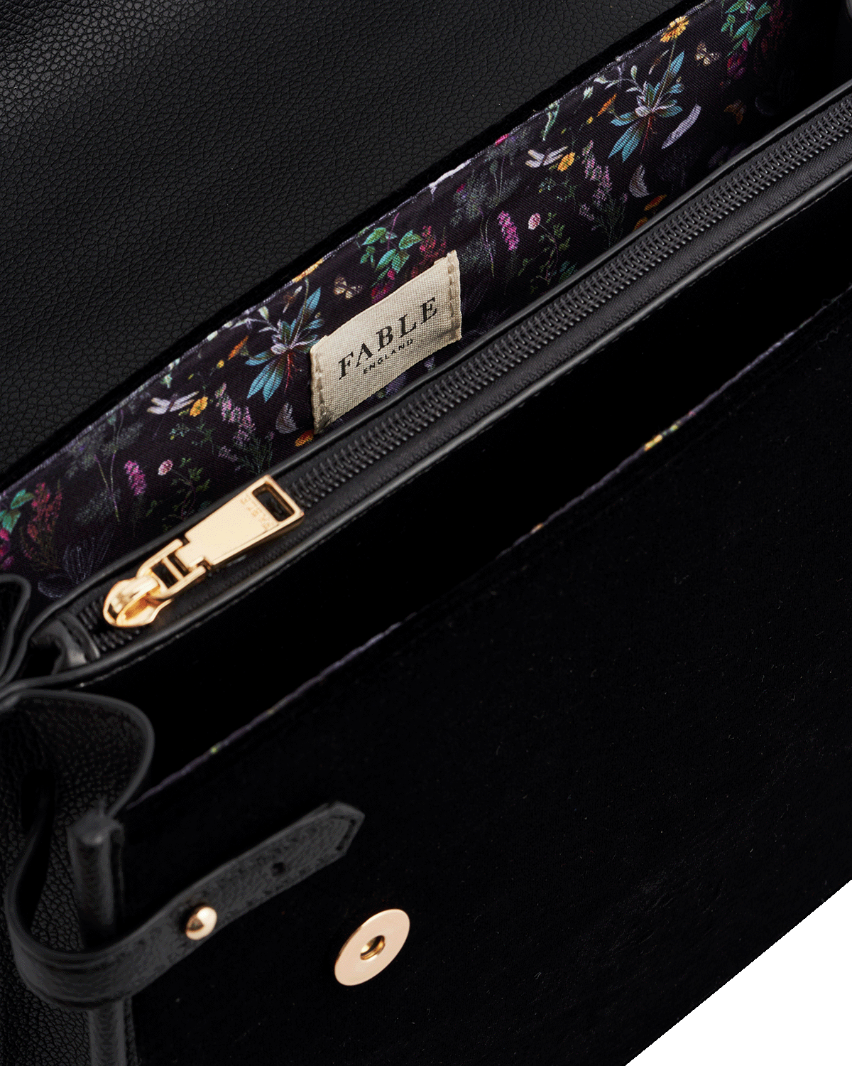 Close-up of a black handbag with floral strap and 'Fable England' label.
