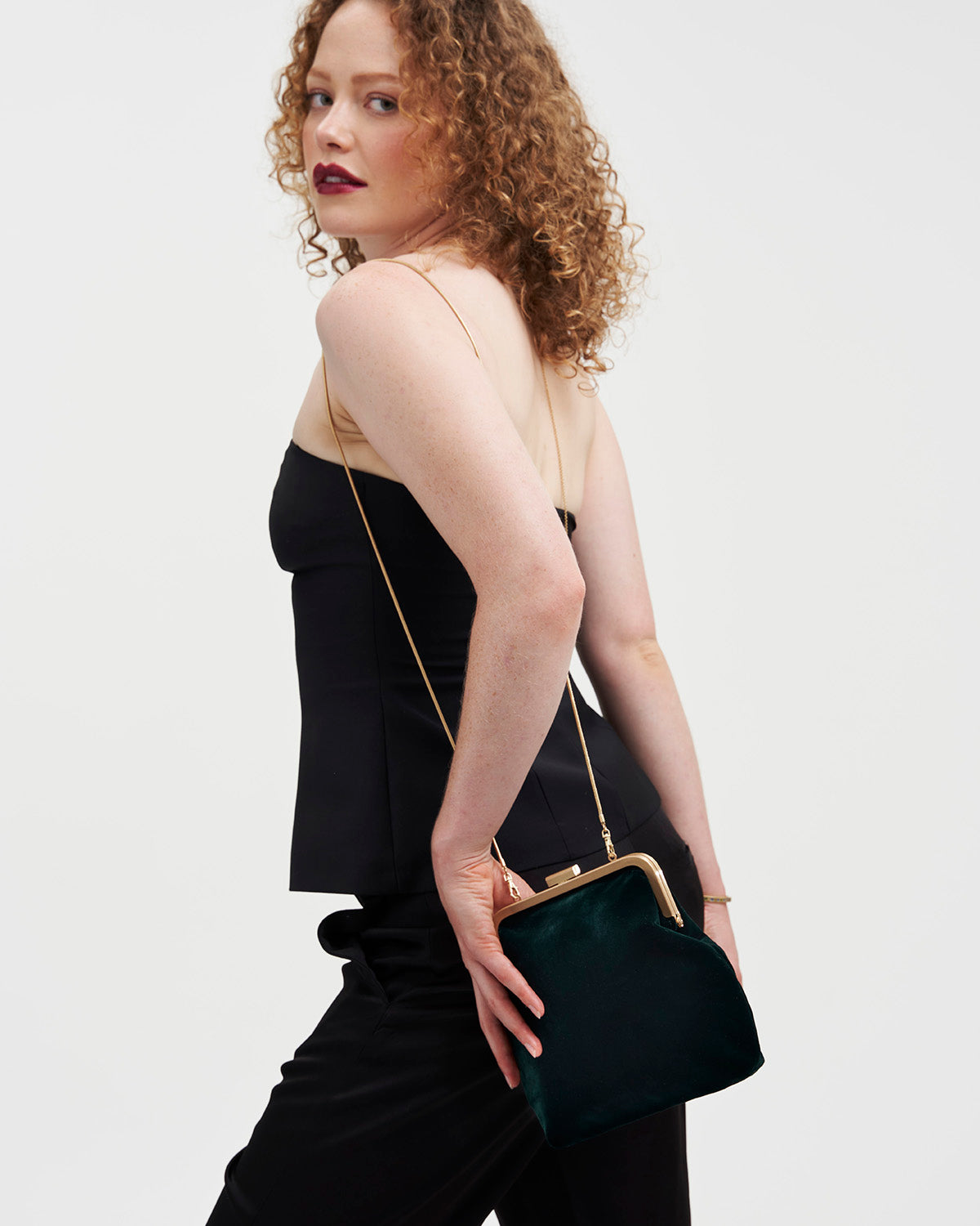 Woman holding a green handbag against a plain background