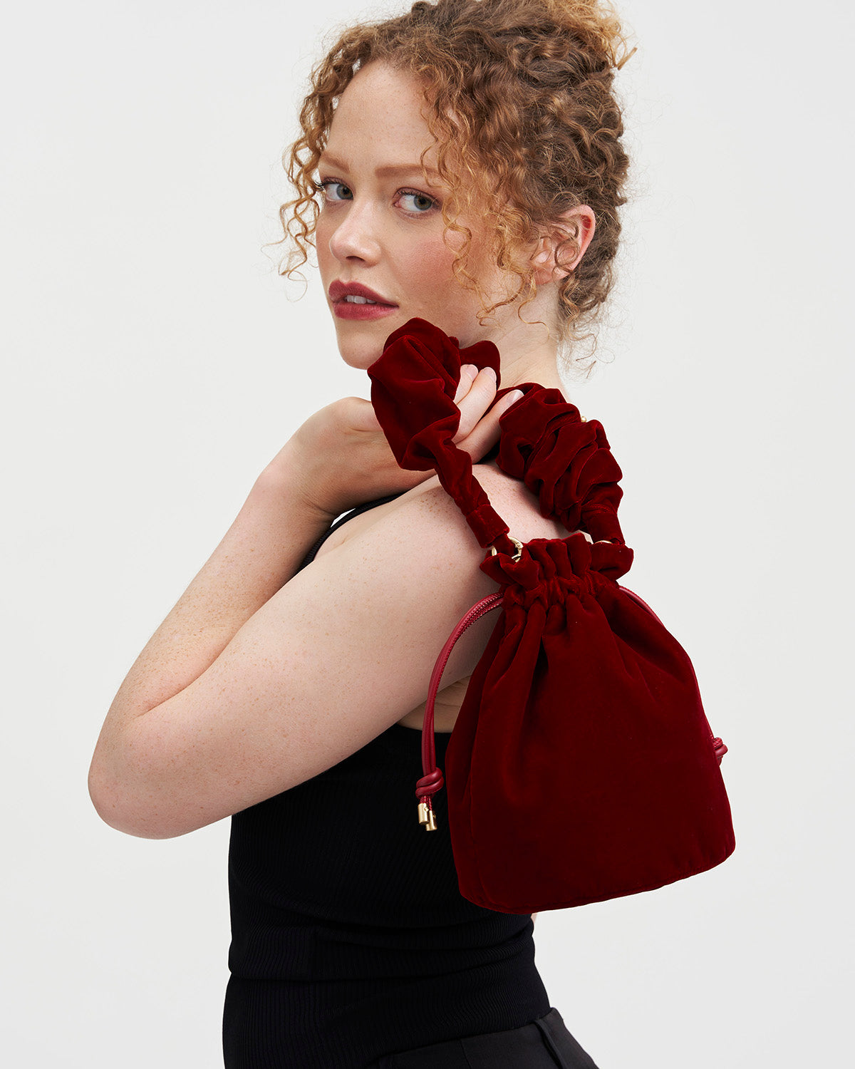 Woman wearing a red velvet bag over her shoulder against a white background