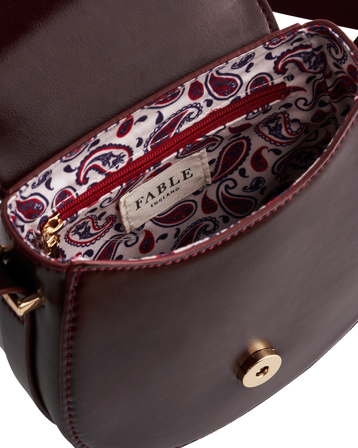 Close-up of a Cherry red handbag with paisley patterned interior and 'Fable England' brand label.