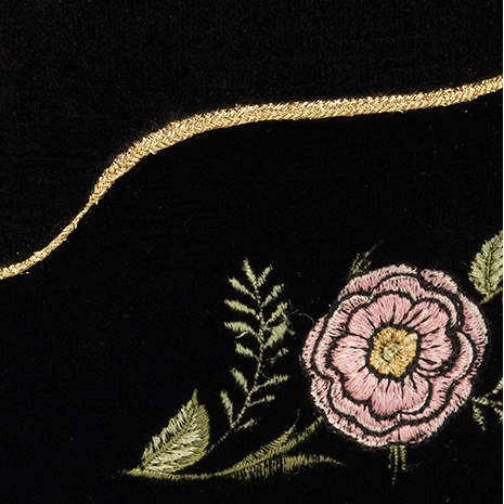 Black clutch bag with floral embroidery and a gold clasp on a white background