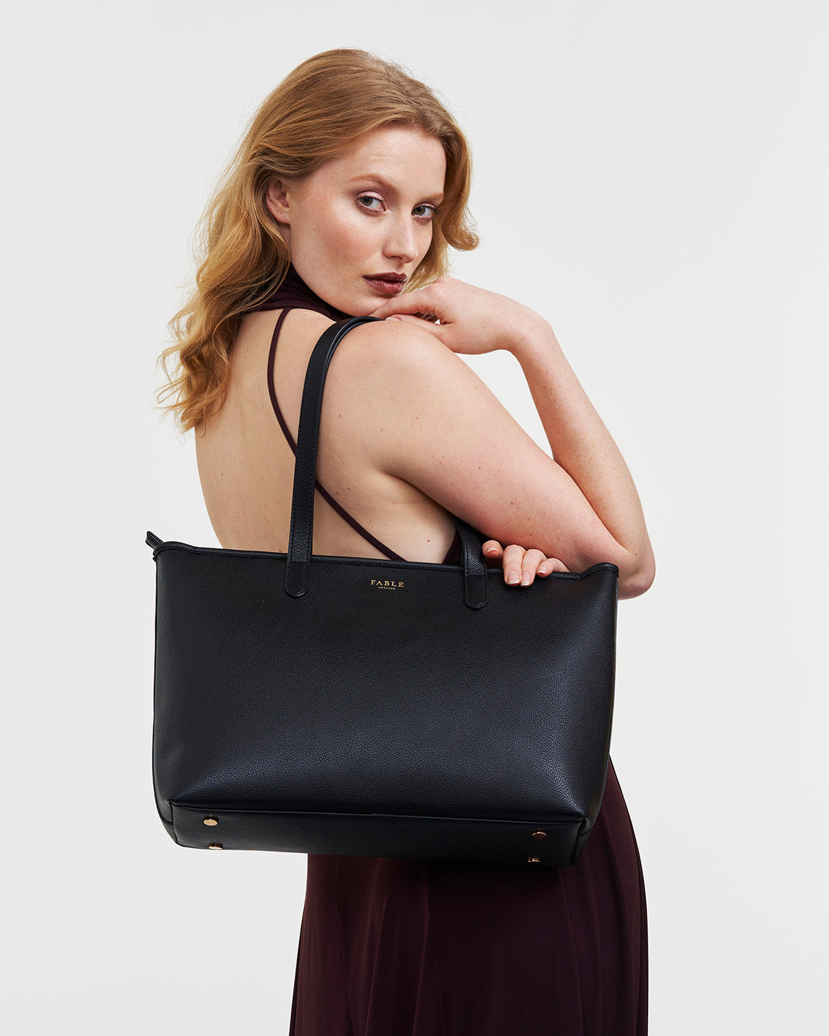 Woman holding a black handbag with a plain background