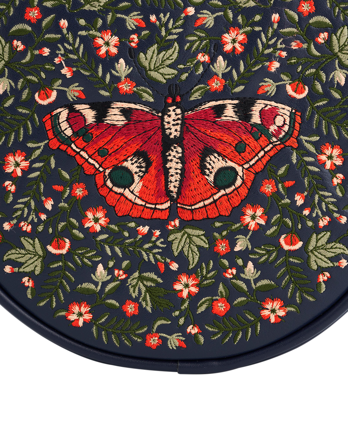 Embroidered design of a red butterfly on a dark background with floral patterns