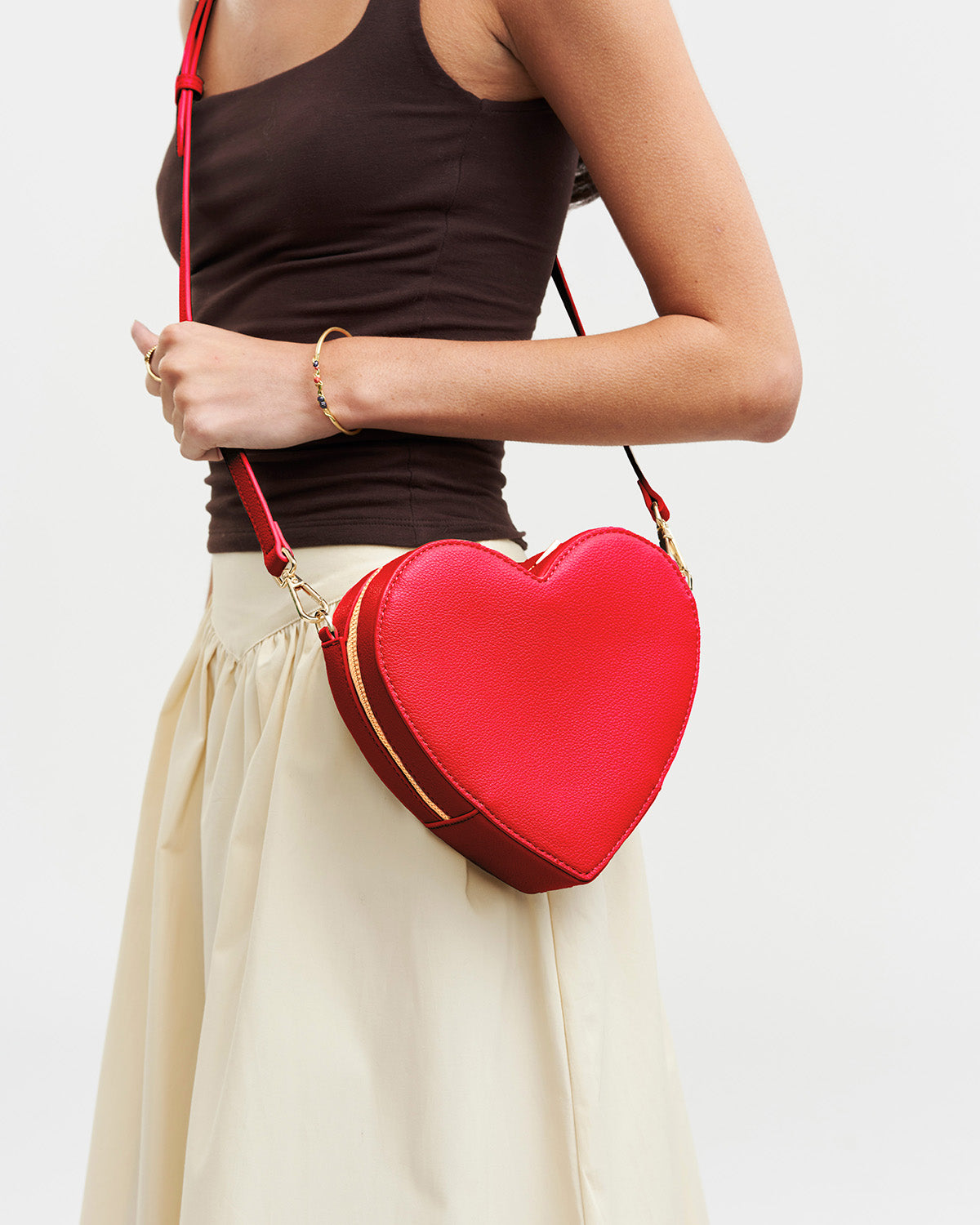 Person holding a red heart-shaped bag against a plain background