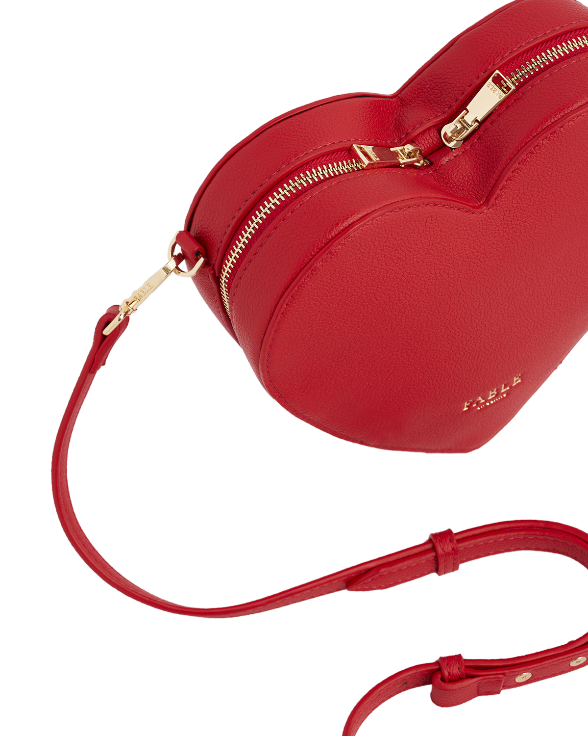 Red heart-shaped handbag with gold zipper on a white background