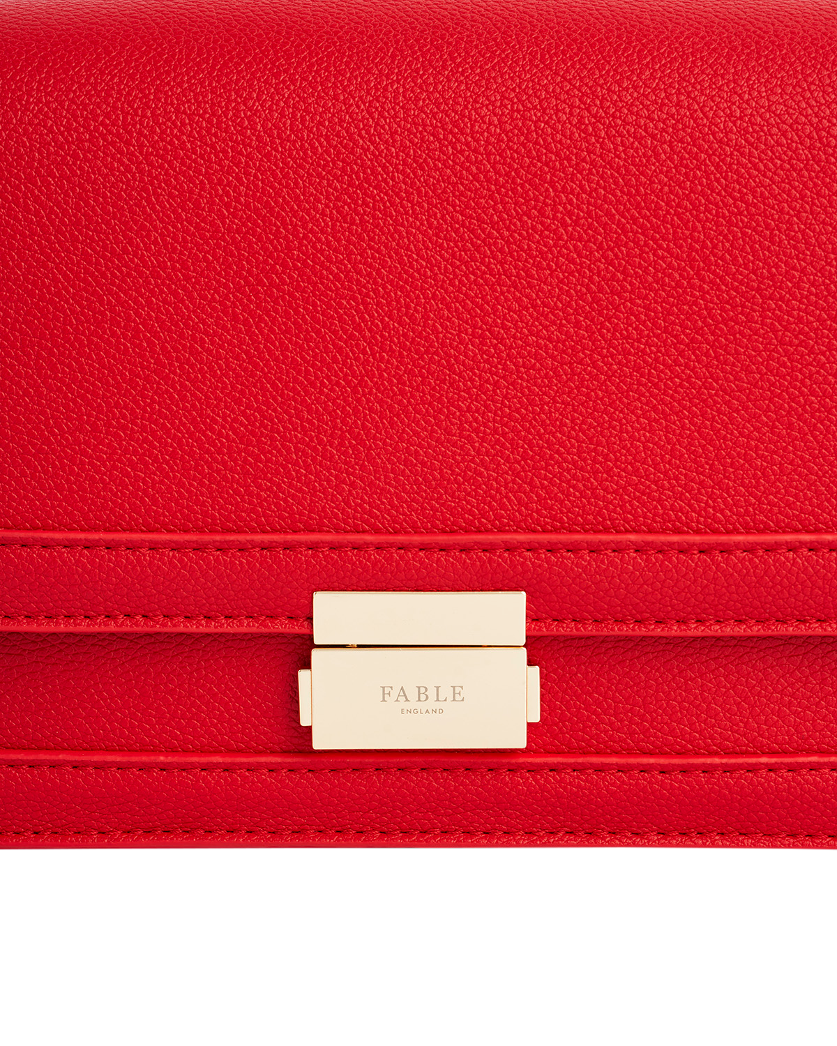 Red handbag with a gold clasp and 'FABLE' branding on a white background