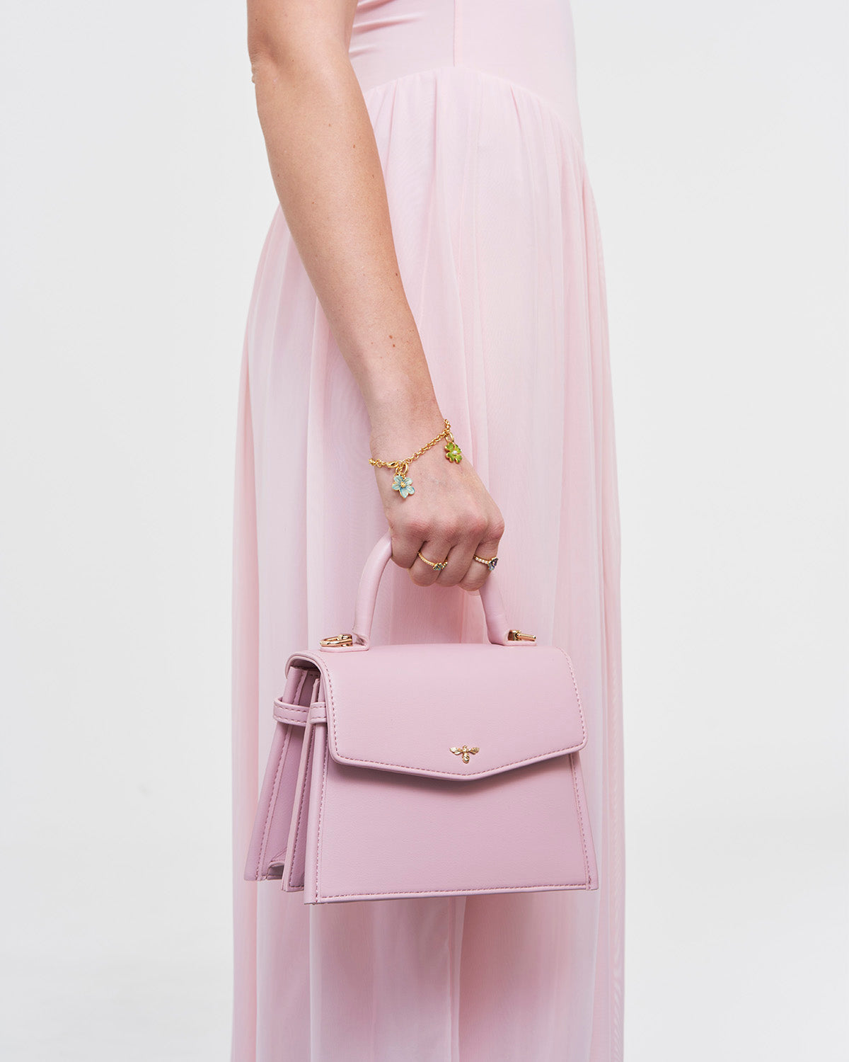 Pink handbag held by a person wearing a pink dress on a light pink background