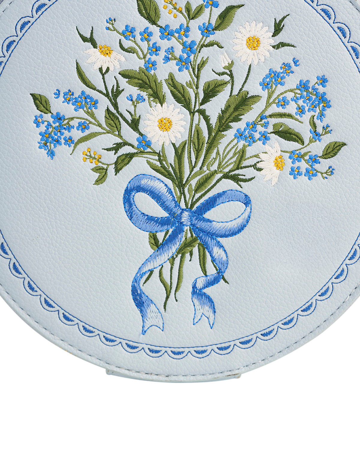 Embroidered design of flowers with a blue bow on a circular background
