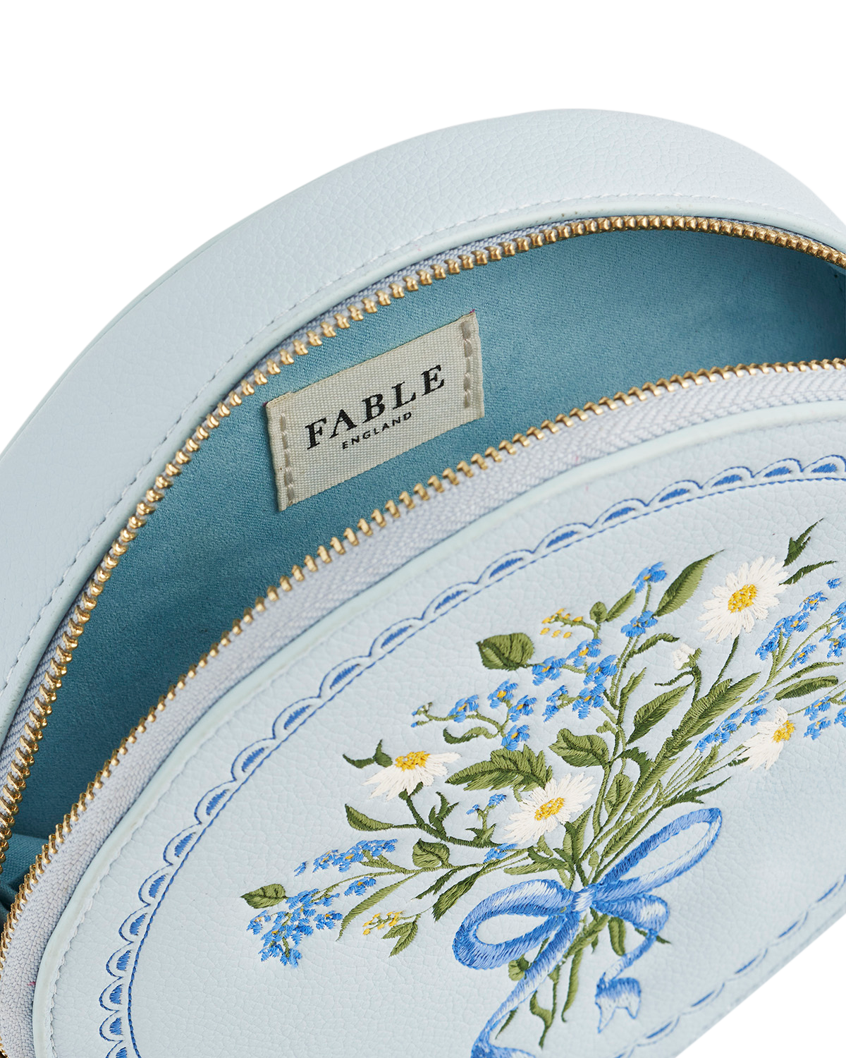 Light blue pouch with floral embroidery and 'Fable' branding