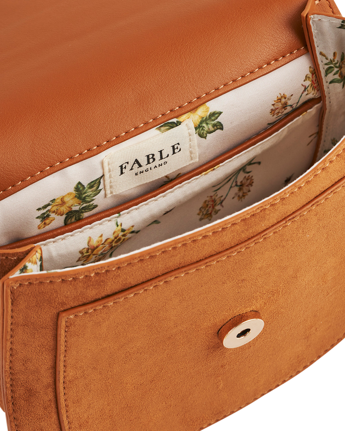 Close-up of a brown leather handbag with floral interior lining and 'Fable' branding.