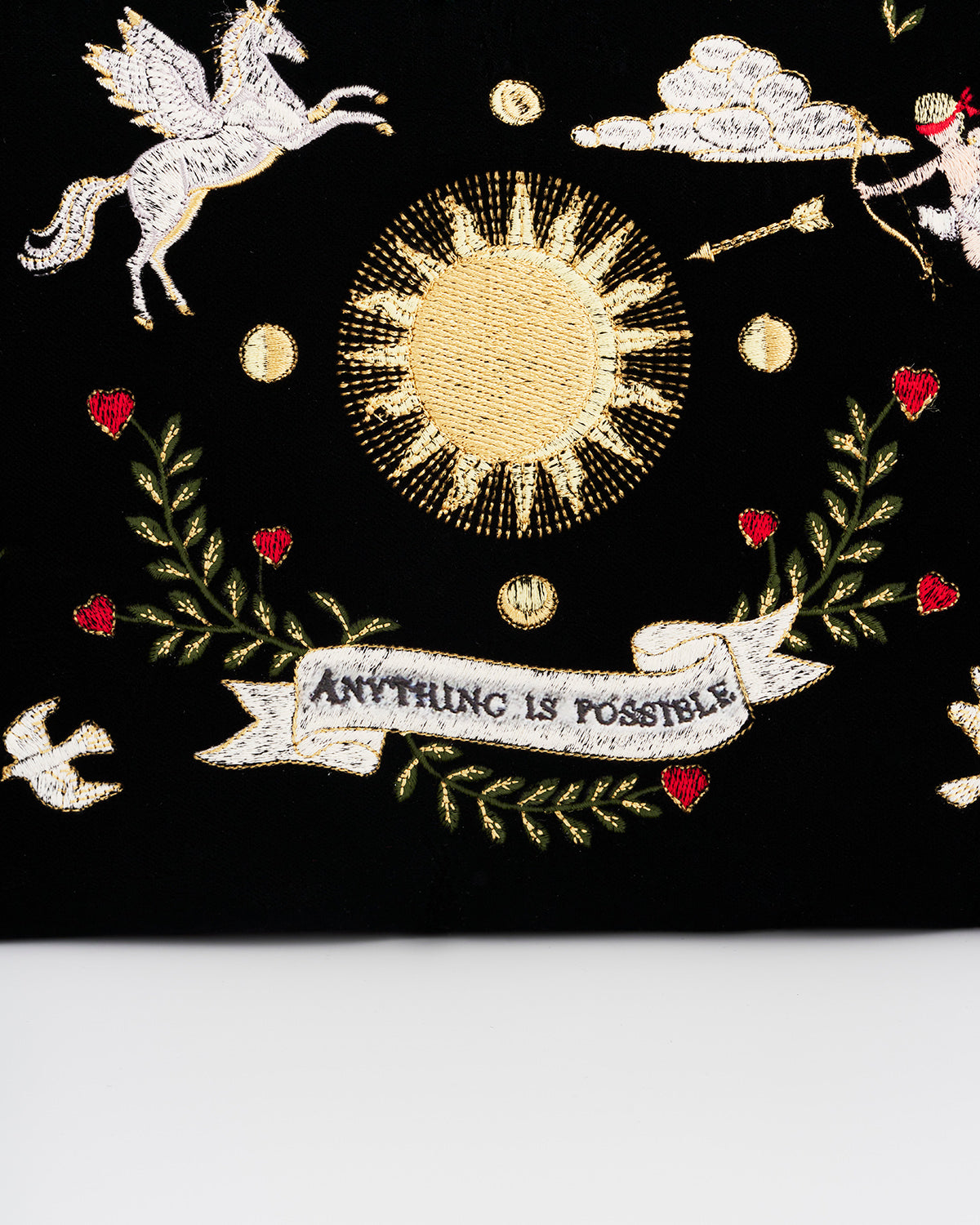 Embroidered design with sun, banner, and decorative elements on a black background
