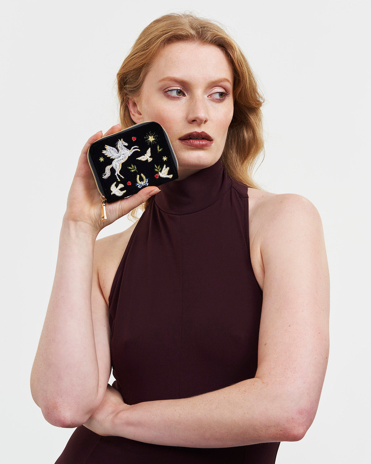 Woman holding a decorative black velvet purse against a plain background