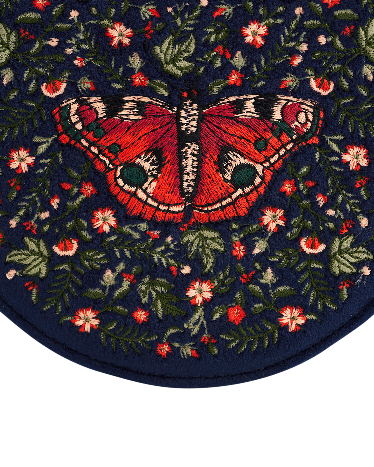 Embroidered butterfly design on a dark blue fabric with flowers and leaves.